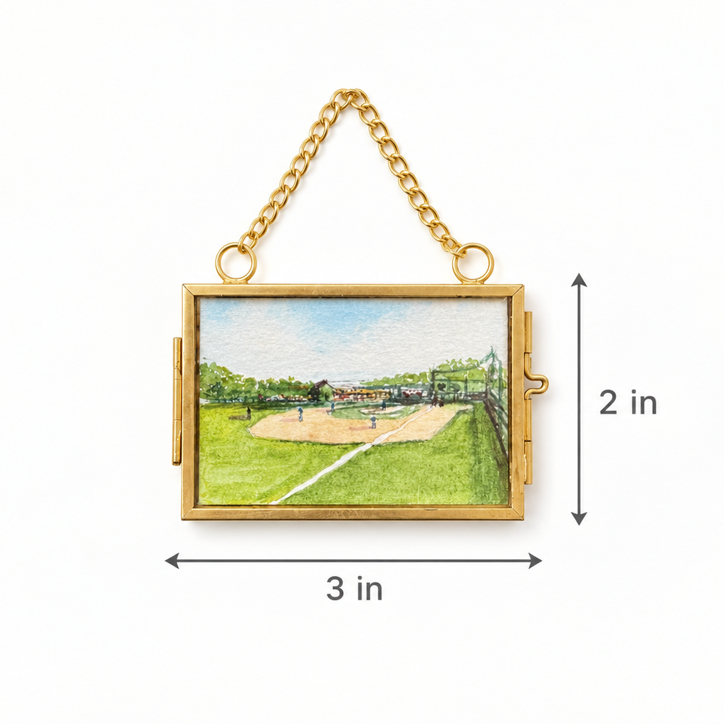A gold-tone rectangular hanging clutch or pouch with a small landscape painting inset showing a baseball field, overlaid with dimension arrows and labels reading 3 in wide and 2 in tall on a white background.